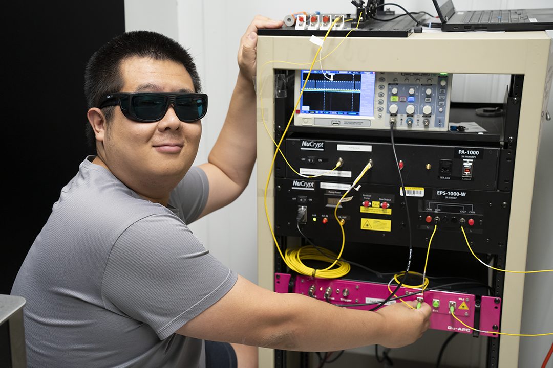 NIST physicist Yicheng Shi at the optical bench used to generate and measure the entangled photon pairs sent across 62 km of commercial fiber between Gaithersburg and College Park, Maryland.