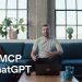 Title card from the OpenAI announcement video: a man sits on a blue sofa in a loft with tall windows and potted plants, a laptop open on the coffee table in front of him, with the words WebMCP in ChatGPT in large white type across the lower left.
