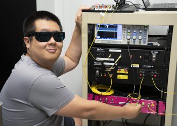 NIST physicist Yicheng Shi, lead author of the study, working at the optical bench used to generate and measure the entangled photon pairs sent across 62 km of commercial fiber between Gaithersburg and College Park, Maryland.