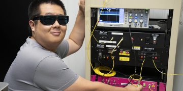 NIST physicist Yicheng Shi, lead author of the study, working at the optical bench used to generate and measure the entangled photon pairs sent across 62 km of commercial fiber between Gaithersburg and College Park, Maryland.