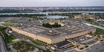 Aerial view of the Pentagon in Arlington, Virginia, at dusk, with the Potomac River and the Washington Monument in the background