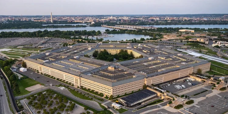 Aerial view of the Pentagon in Arlington, Virginia, at dusk, with the Potomac River and the Washington Monument in the background
