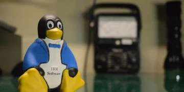 Tux the Linux penguin mascot as a small figurine holding an IBM Software label, on a workbench