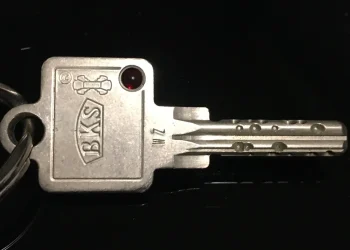 Close-up of a metal door key on a keyring against a black background