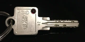 Close-up of a metal door key on a keyring against a black background