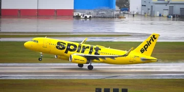 A yellow Spirit Airlines Airbus A320 lifting off from a wet runway at Tampa International Airport