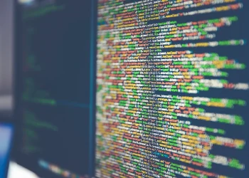 Close-up of a monitor displaying colorful JavaScript source code, shallow depth of field