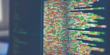 Close-up of a monitor displaying colorful JavaScript source code, shallow depth of field