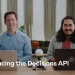 OpenAI's announcement video still for the Decisions API: two presenters at a table with laptops and the caption 'Introducing the Decisions API'
