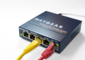 Netgear 5-port gigabit Ethernet switch with a yellow and a red cable plugged into its ports