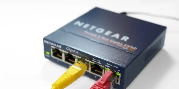 Netgear 5-port gigabit Ethernet switch with a yellow and a red cable plugged into its ports