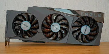 Gigabyte GeForce RTX 3090 Eagle OC 24G graphics card with three fans standing on a wooden table in front of a textured white wall