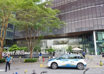 Entrance of the Tencent Binhai Building in Shenzhen with the Tencent sign, trees and a taxi in the foreground