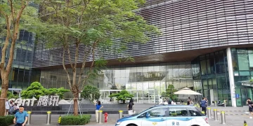 Entrance of the Tencent Binhai Building in Shenzhen with the Tencent sign, trees and a taxi in the foreground