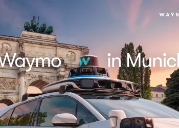 Waymo robotaxi with its roof sensor dome in front of the Siegestor victory arch in Munich, under the title Waymo in Munich