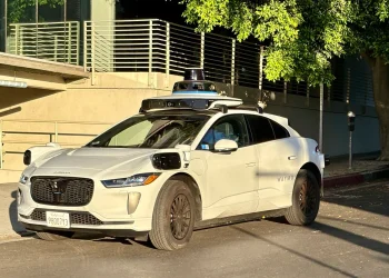 White Waymo Jaguar I-Pace robotaxi with a roof sensor dome parked on a street in Century City, Los Angeles
