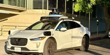 White Waymo Jaguar I-Pace robotaxi with a roof sensor dome parked on a street in Century City, Los Angeles