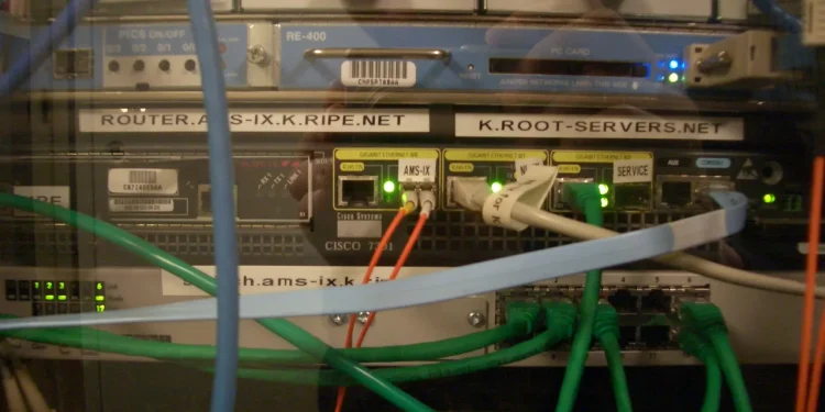 Rack of network equipment labelled K.ROOT-SERVERS.NET, the AMS-IX mirror of the K DNS root server, with Cisco router and patch cables